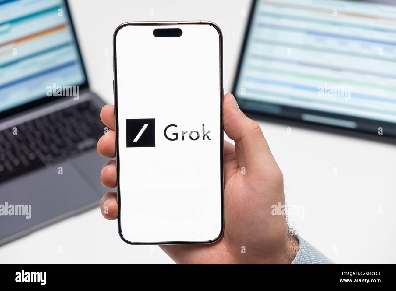 PRAG, TSCHECHISCHE REPUBLIK - 21. JANUAR 2024: Grok-Logo auf dem Bildschirm des Smartphones in der Hand des Mannes auf dem Hintergrund des Arbeitsplatzes. Stockfoto