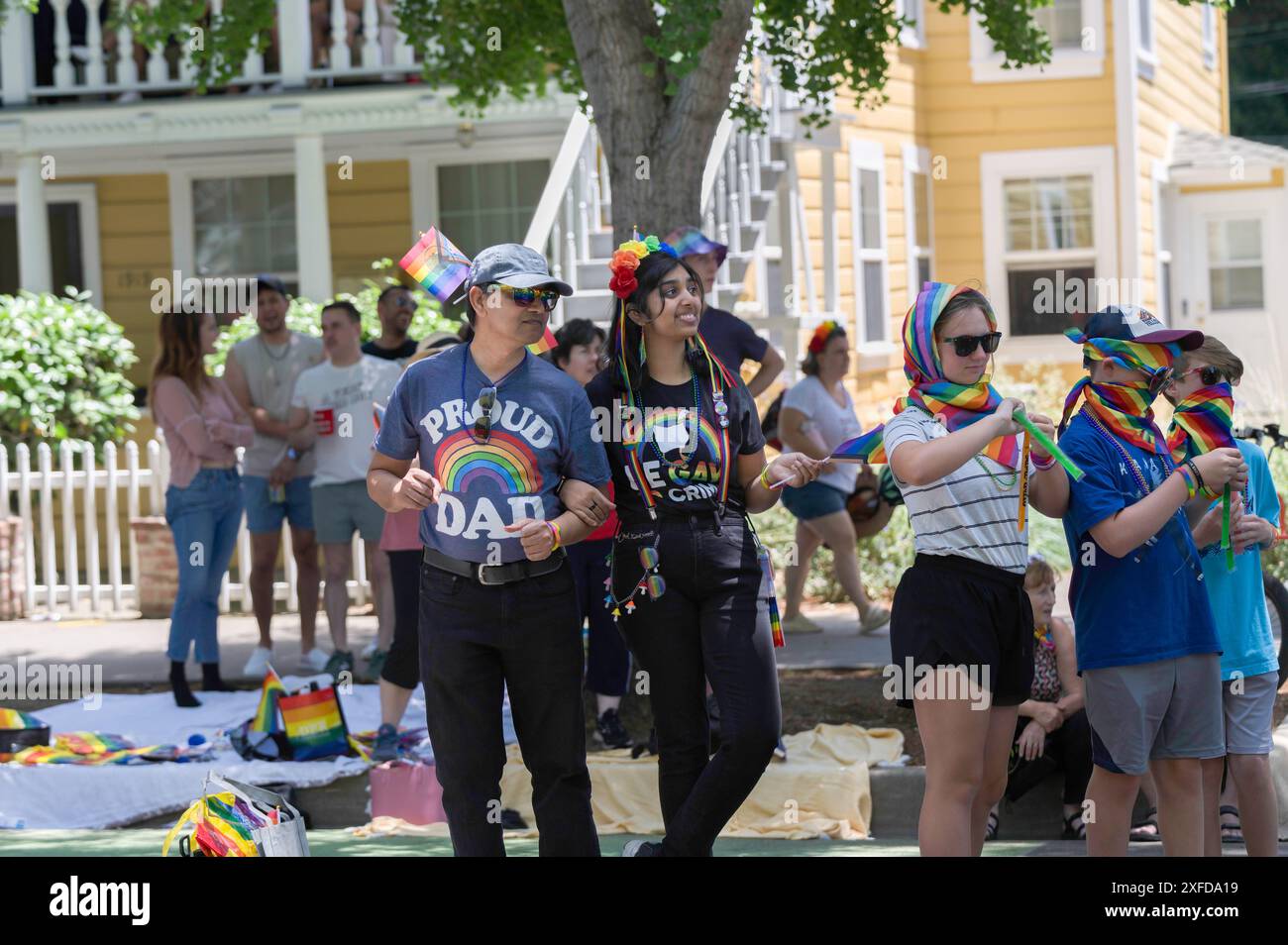 Ein Mann, der bei der jährlichen Sacramento Pride Parade ein Regenbogenhemd trägt, verbindet die Arme mit einem anderen Paradebeobachter. Stockfoto