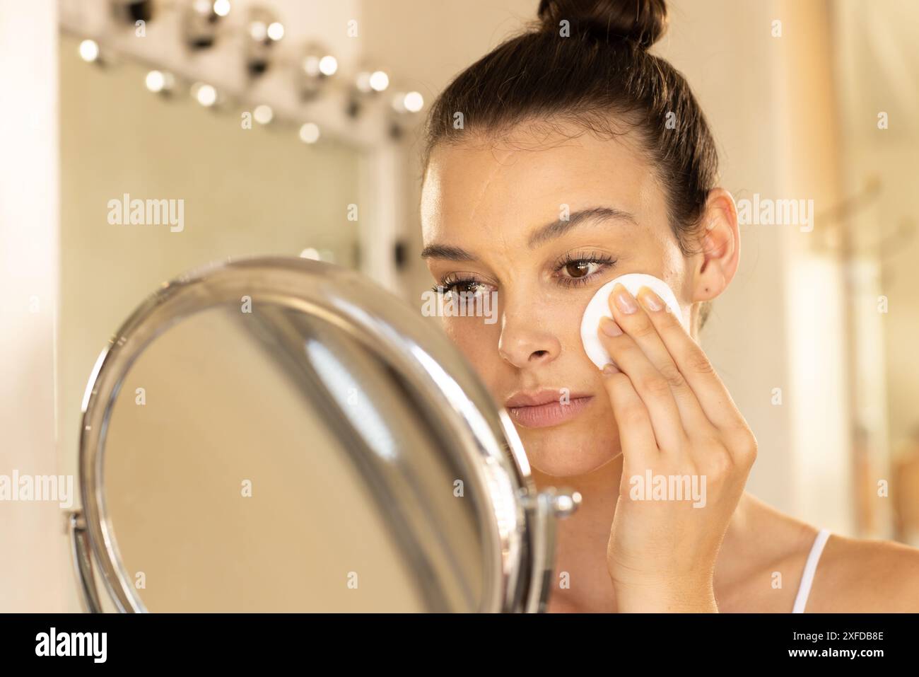 Make-up auftragen, junge Frau mit Wattepad vor dem Spiegel Stockfoto