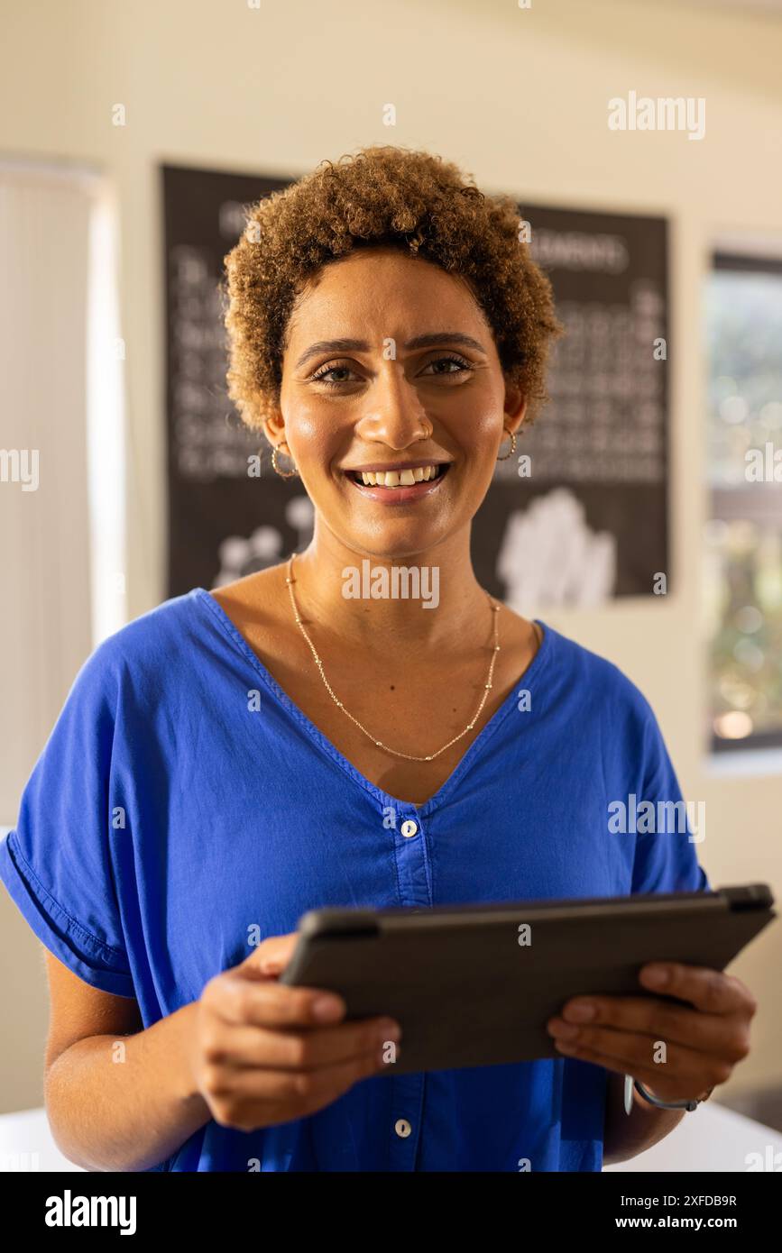 Ein Tablet in der Hand, ein Lehrer lächelt im Klassenzimmer, bereit für den Unterricht in der Highschool Stockfoto