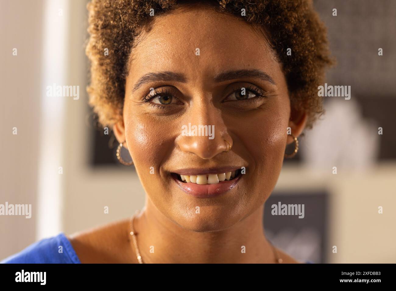 Lächelnder Lehrer in der High School, Nahporträt mit lockigen Haaren und Ohrringen Stockfoto