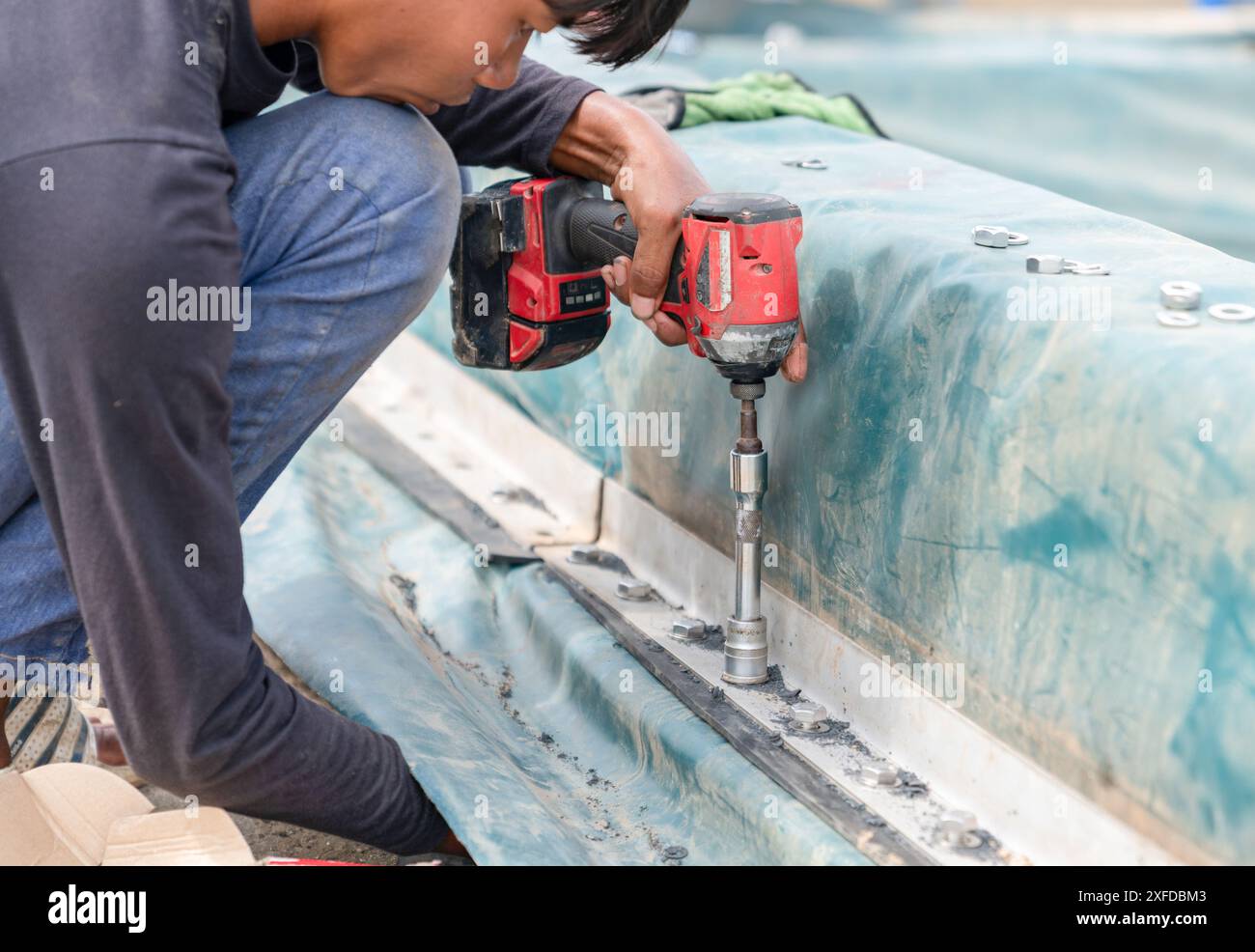 Arbeiter verwenden einen drahtlosen Schraubendreher. Ziehen Sie die Kante der Dichtung der Abwasserkuppel im Werk fest. Stockfoto