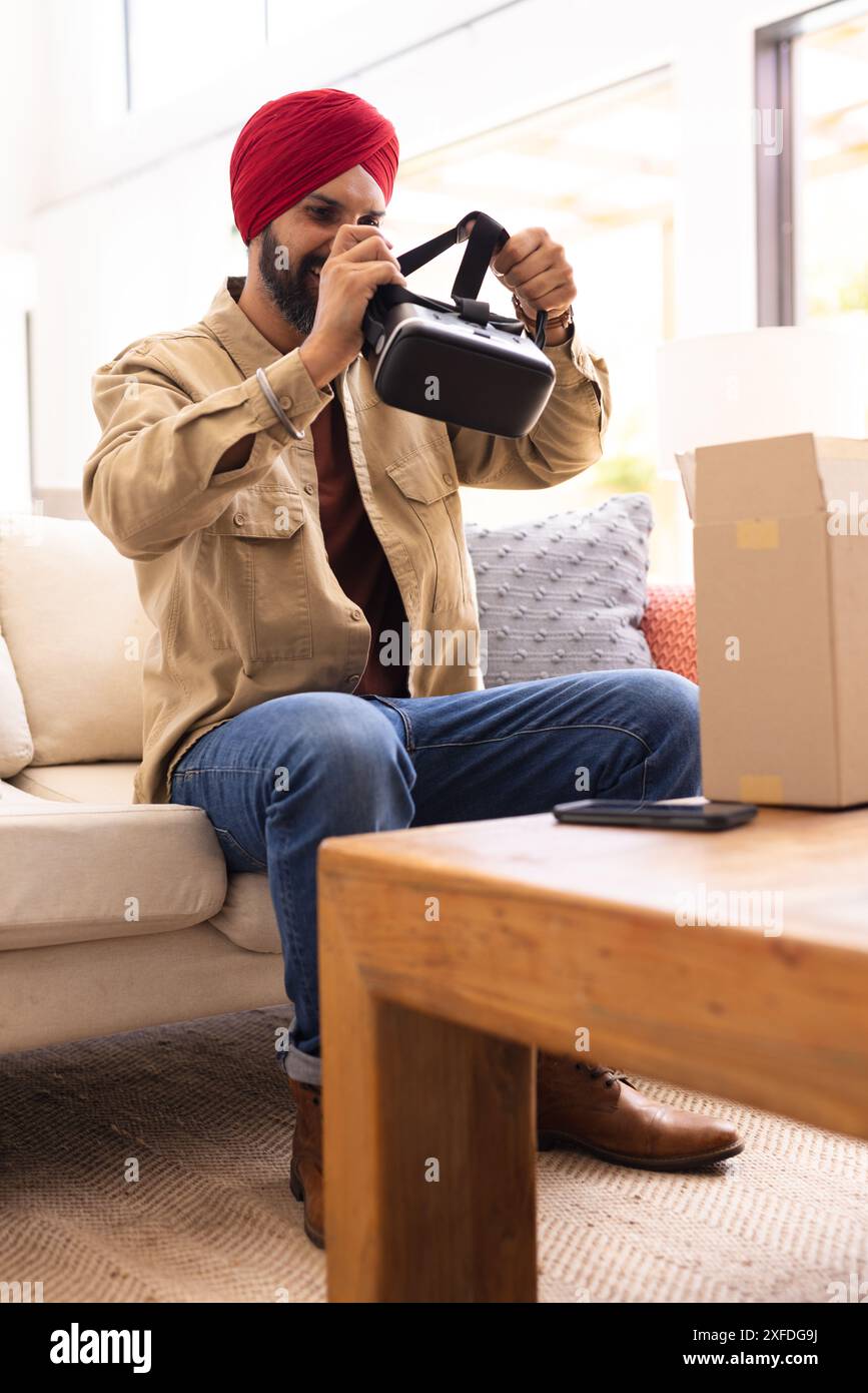 Das VR-Headset wird ausgepackt, ein Mann sitzt im Wohnzimmer auf der Couch und erkundet die Technologie Stockfoto