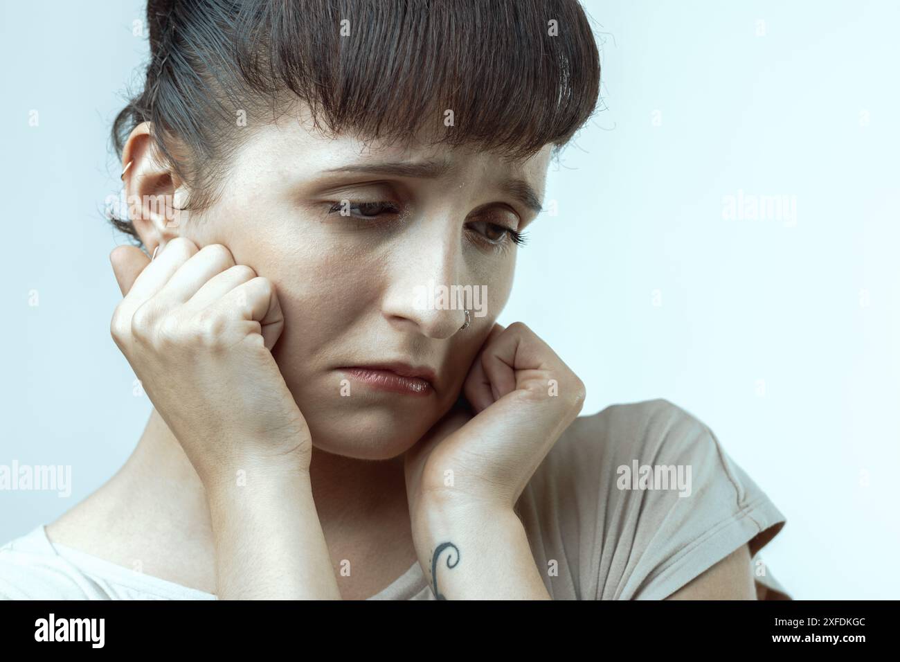 Die beunruhigte junge Frau packt sich mit Emotionen und versucht, Traurigkeit und Verzweiflung in einem Nahaufnahme-Porträt zu überwinden, das Einsamkeit und Angst zeigt Stockfoto