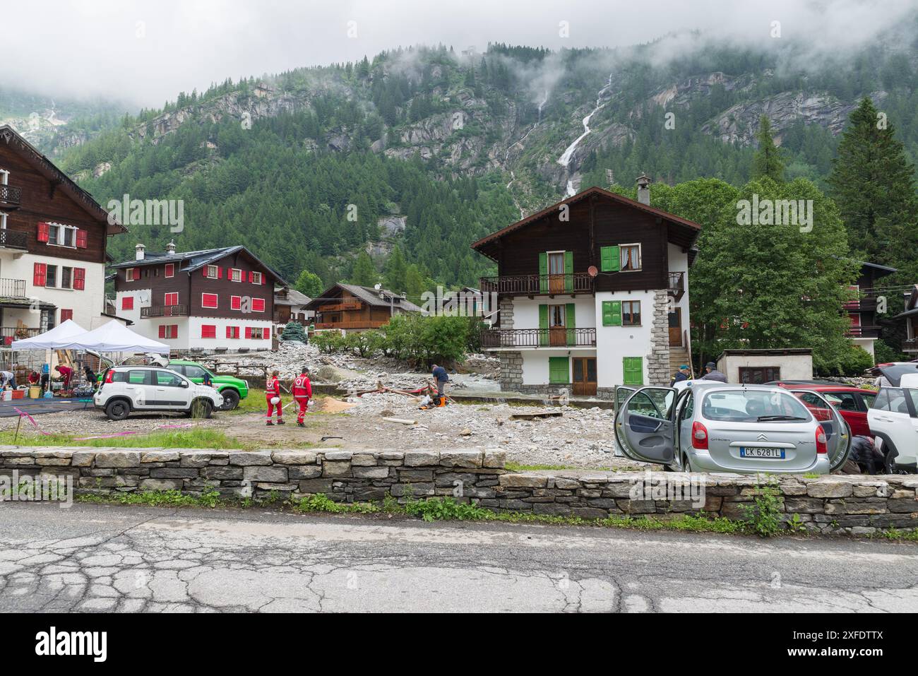 Überflutung eines Flusses, Überschwemmungen und Erdrutsche zwischen Häusern eines Bergdorfes. Konzept des Klimawandels und der Naturkatastrophe. Macugnaga, Italien Stockfoto