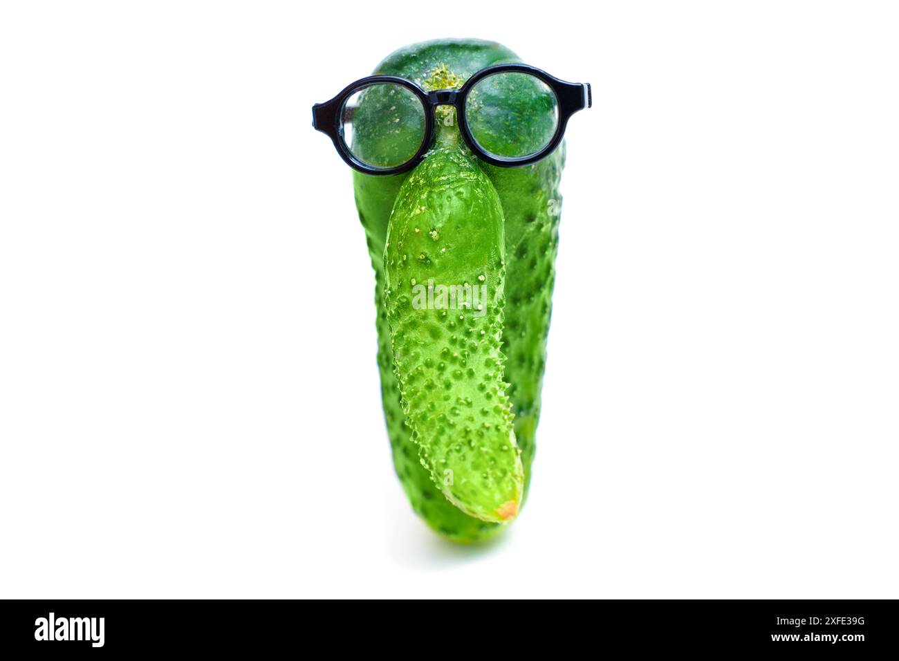 Gurke mit einem markanten Auswuchs, der einer großen Nase ähnelt, mit Brille, vor weißem Hintergrund, symbolisiert das Wissen über die richtige Nuss Stockfoto