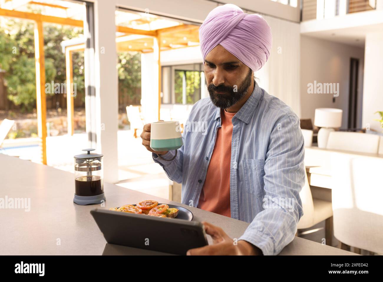 Kaffee trinken und Tablet benutzen, Mann, der zu Hause frühstückt Stockfoto