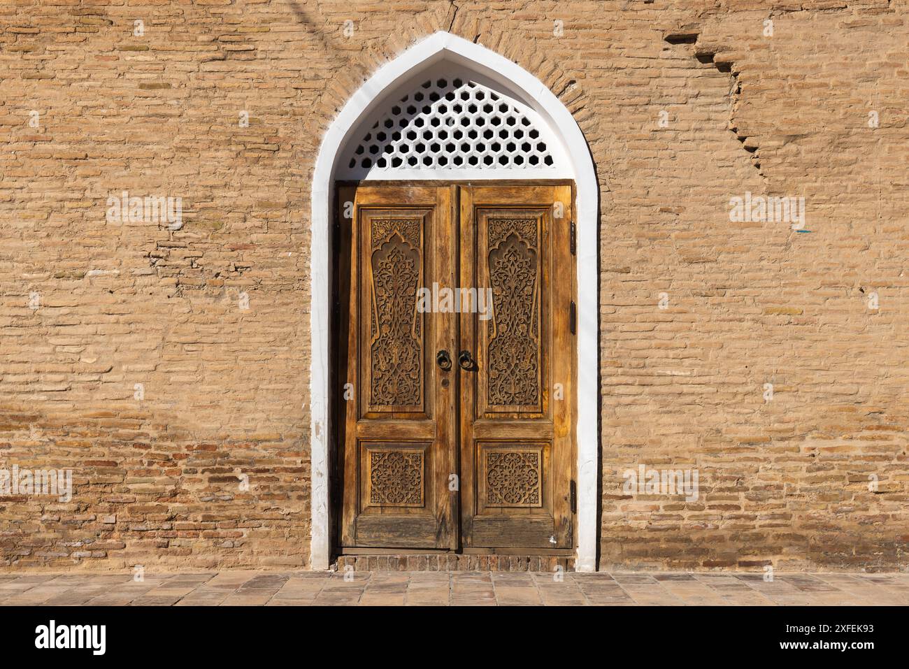 Alte Holztür mit geschnitztem weißen Rahmen und geschnitztem arabischem Muster. Samarkand, Usbekistan Stockfoto