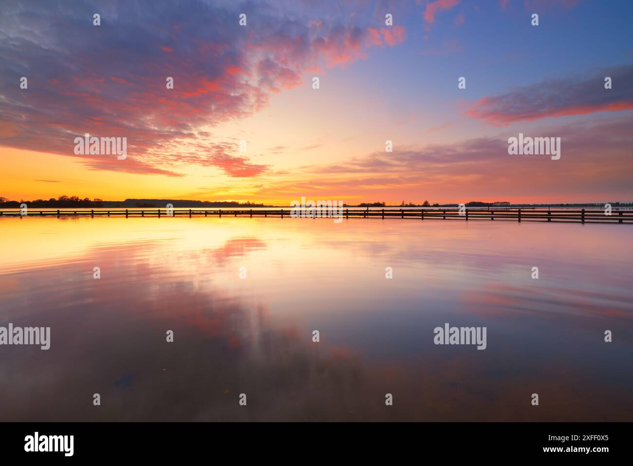 Ein wunderschöner Sonnenuntergang im Veerse Mere in den Niederlanden im Sommer mit lebhaften Farben und spiegelähnlichen Reflexen auf der Wasseroberfläche. Stockfoto