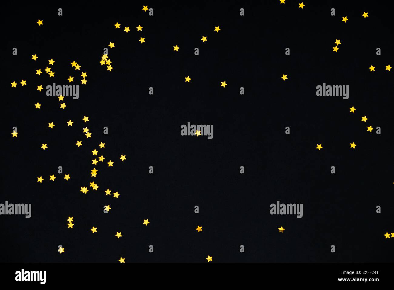 Goldene Glitzersterne Konfetti auf schwarzem Hintergrund. Festliche Weihnachtskulisse in Pastellfarben. Minimales Konzept. Luxuriöse flache Komposition. Stockfoto