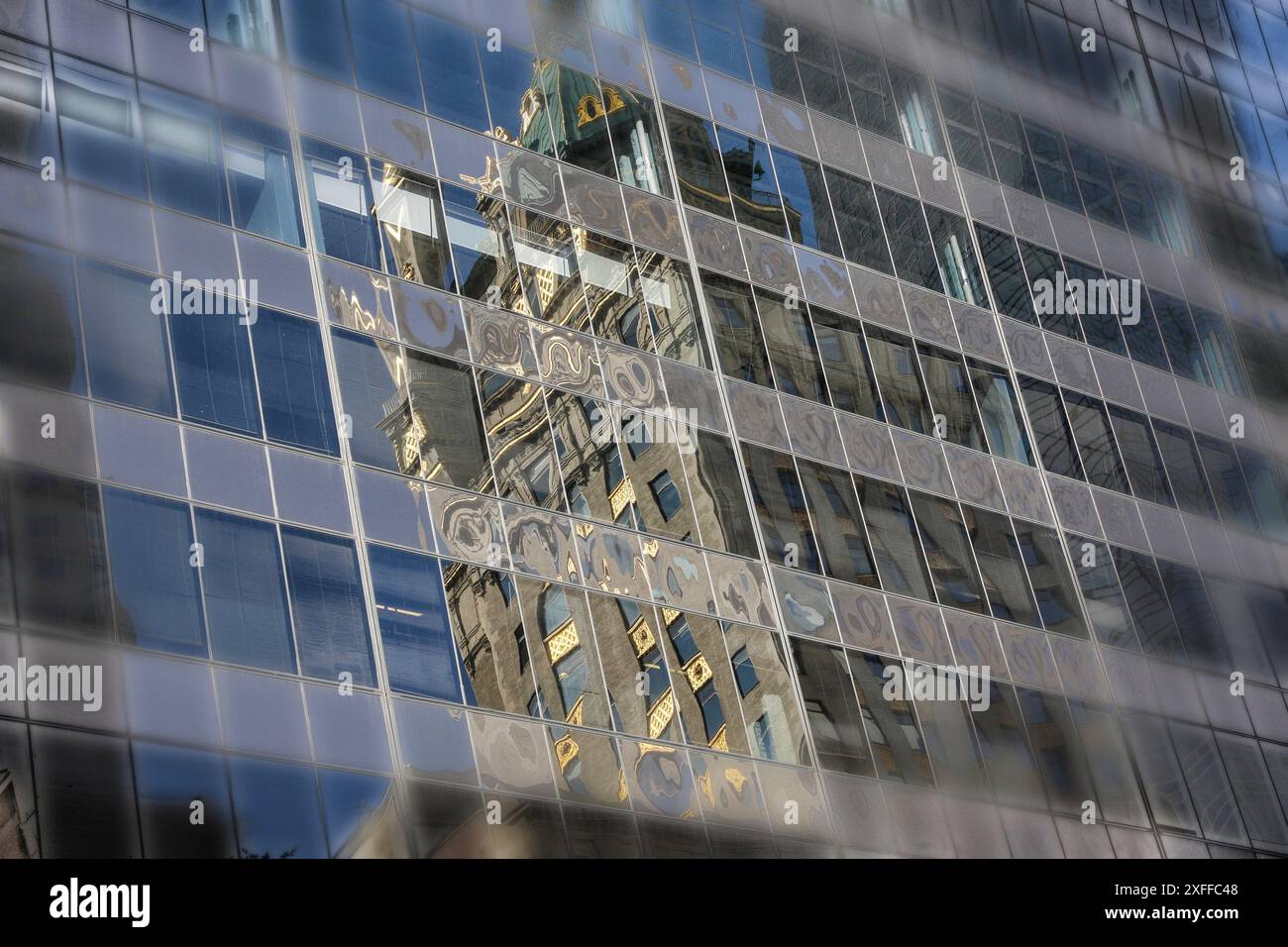 Die verzierte Fassade eines historischen Gebäudes spiegelt sich in den Fenstern eines modernen Wolkenkratzers wider und schafft einen faszinierenden städtischen Wandteppich architektonischer Vielfalt. Stockfoto