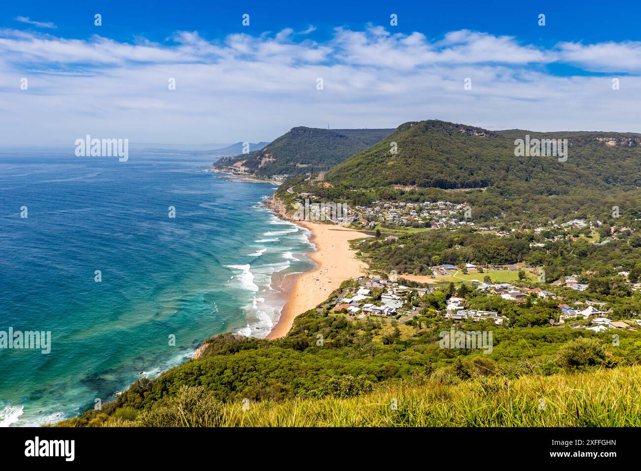 Ein wunderschöner Blick aus der Vogelperspektive auf Clifton und Sea Cliff Bridge mit Sandstrand und Wellen, die an der Küste krachen. Der Strand wird von üppigen grünen Klippen A begrenzt Stockfoto