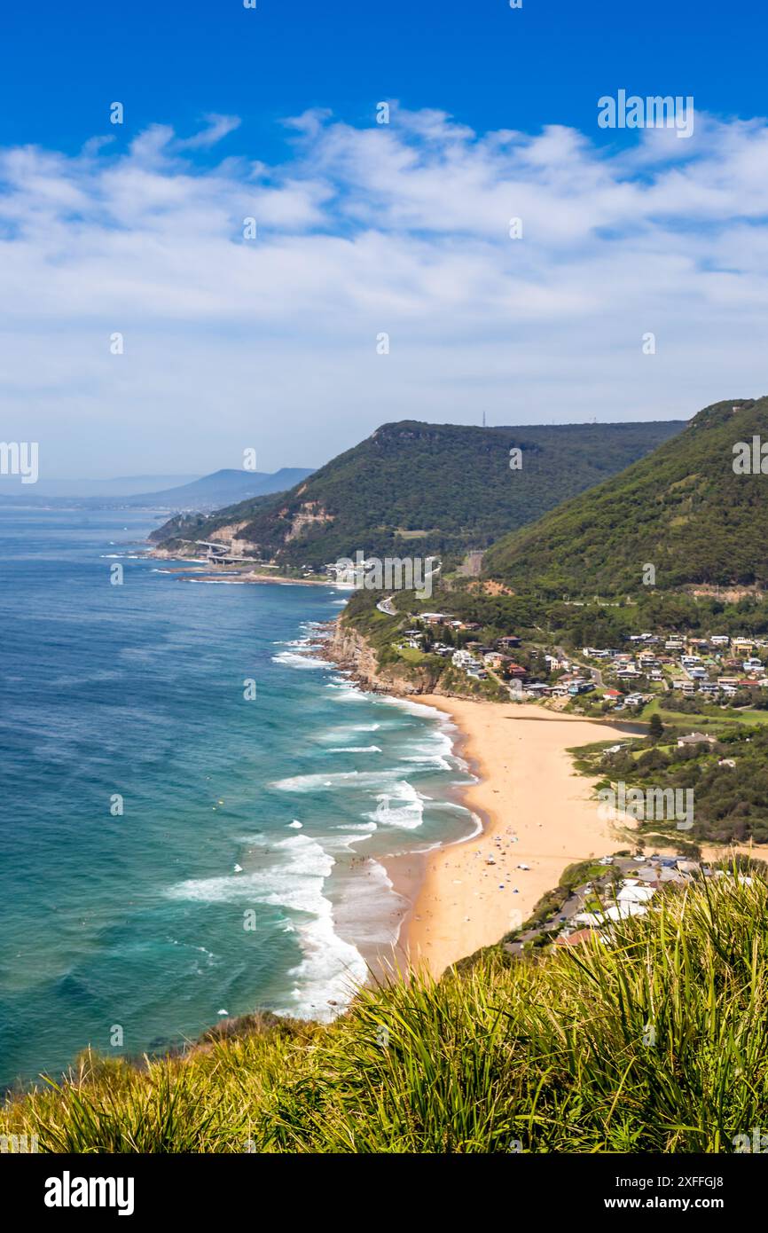 Ein wunderschöner Blick aus der Vogelperspektive auf Clifton und Sea Cliff Bridge mit Sandstrand und Wellen, die an der Küste krachen. Der Strand wird von üppigen grünen Klippen A begrenzt Stockfoto