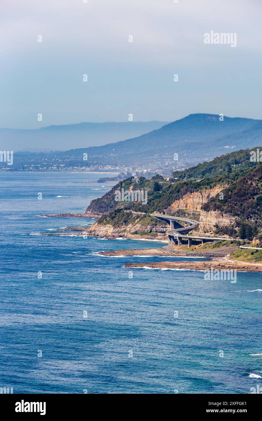 Ein wunderschöner Blick aus der Vogelperspektive auf Clifton und Sea Cliff Bridge mit Sandstrand und Wellen, die an der Küste krachen. Der Strand wird von üppigen grünen Klippen A begrenzt Stockfoto