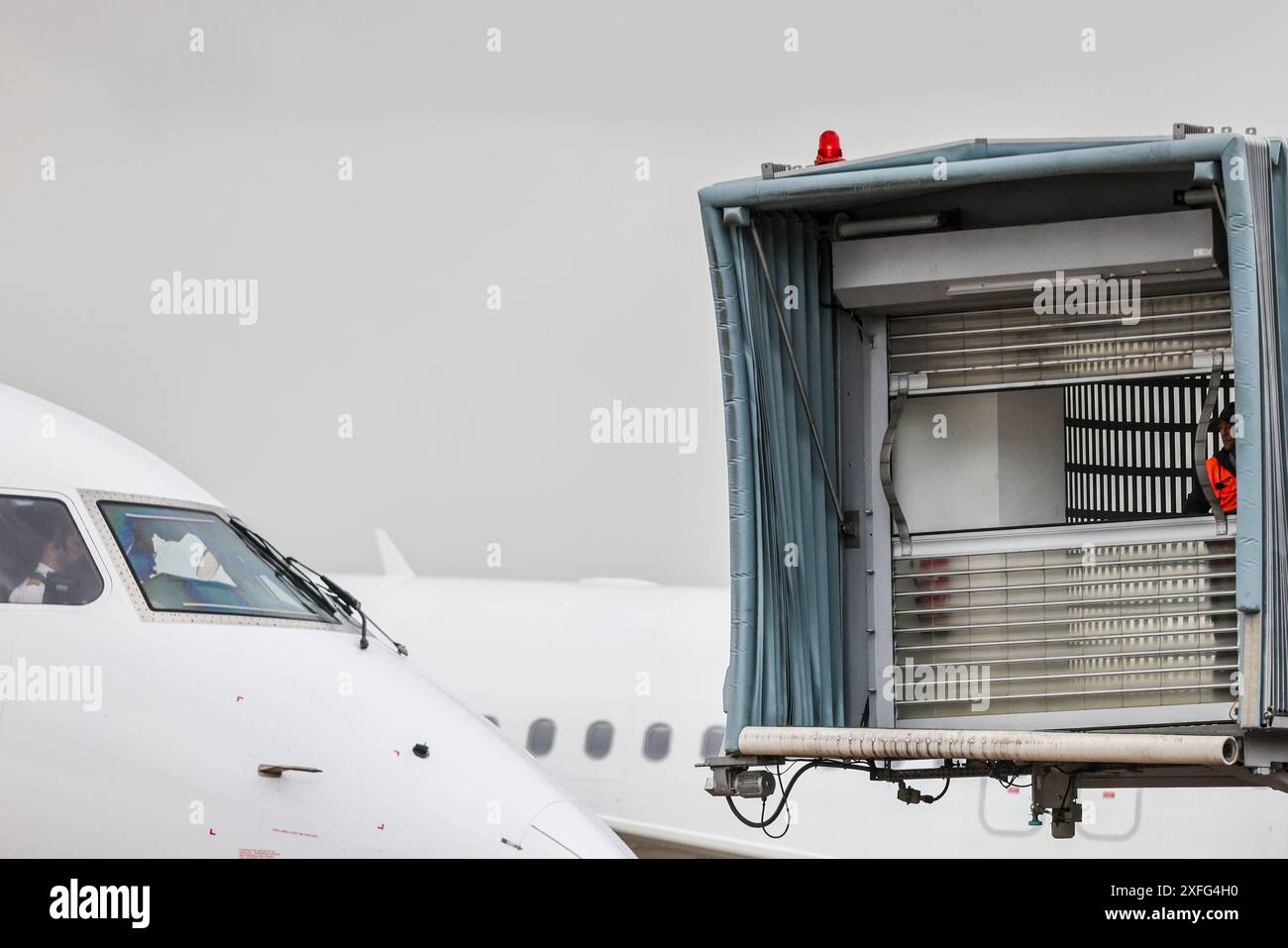 03. Juli 2024, Nordrhein-Westfalen, Düsseldorf: Der Finger, an dem Passagiere nach Landung eines Flugzeugs aussteigen, wird auf ein Flugzeug manövriert. Foto: Christoph Reichwein/dpa Stockfoto