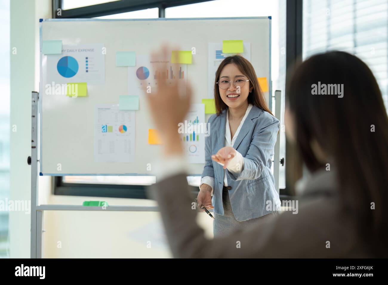 Geschäftsfrau führt eine Präsentation im modernen Büro mit Diagrammen und Diagrammen auf Whiteboard Stockfoto