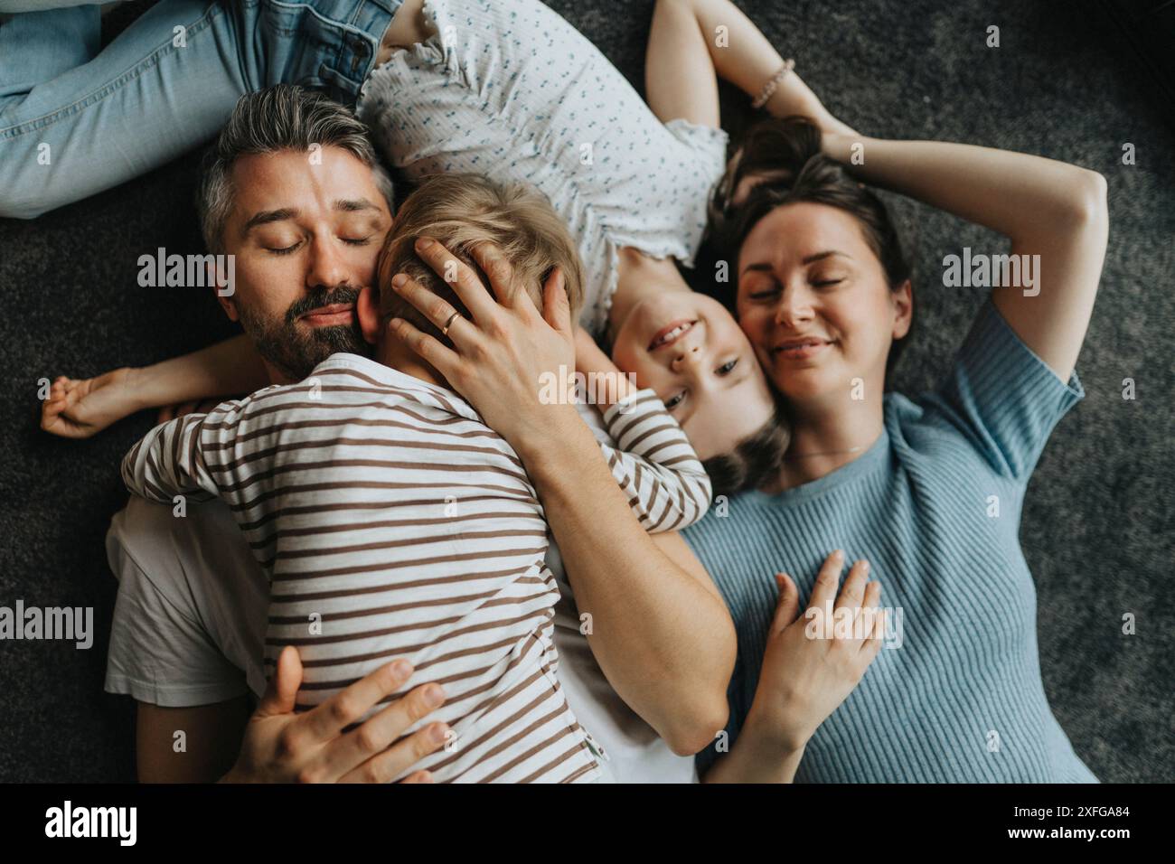 Direkt über der Aufnahme von Eltern, die Sohn und Tochter umarmen, während sie zu Hause auf dem Boden liegen Stockfoto