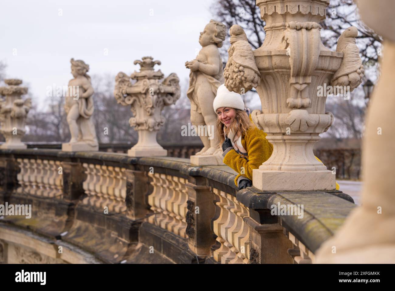 Eine junge Touristin im gelben Mantel schaut nach draußen. Glückliche Reisende Frau, die die Touristenattraktionen von Dresden, Deutschland, ansieht Stockfoto