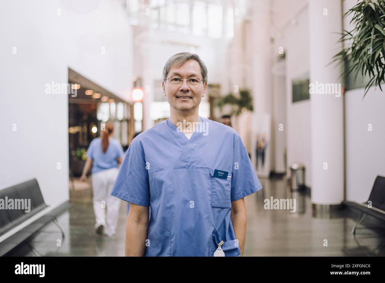 Porträt eines lächelnden männlichen Arztes, der in der Krankenhauslobby steht Stockfoto
