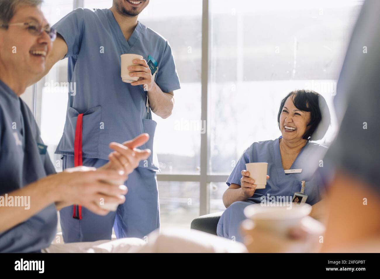 Glückliche männliche und weibliche medizinische Fachkräfte, die Spaß während der Kaffeepause im Krankenhaus haben Stockfoto