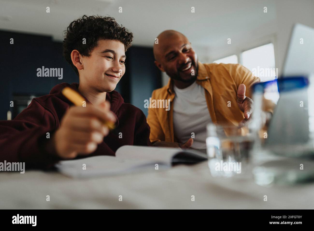 Glücklicher Vater, der seinem Sohn hilft, Hausaufgaben zu machen Stockfoto