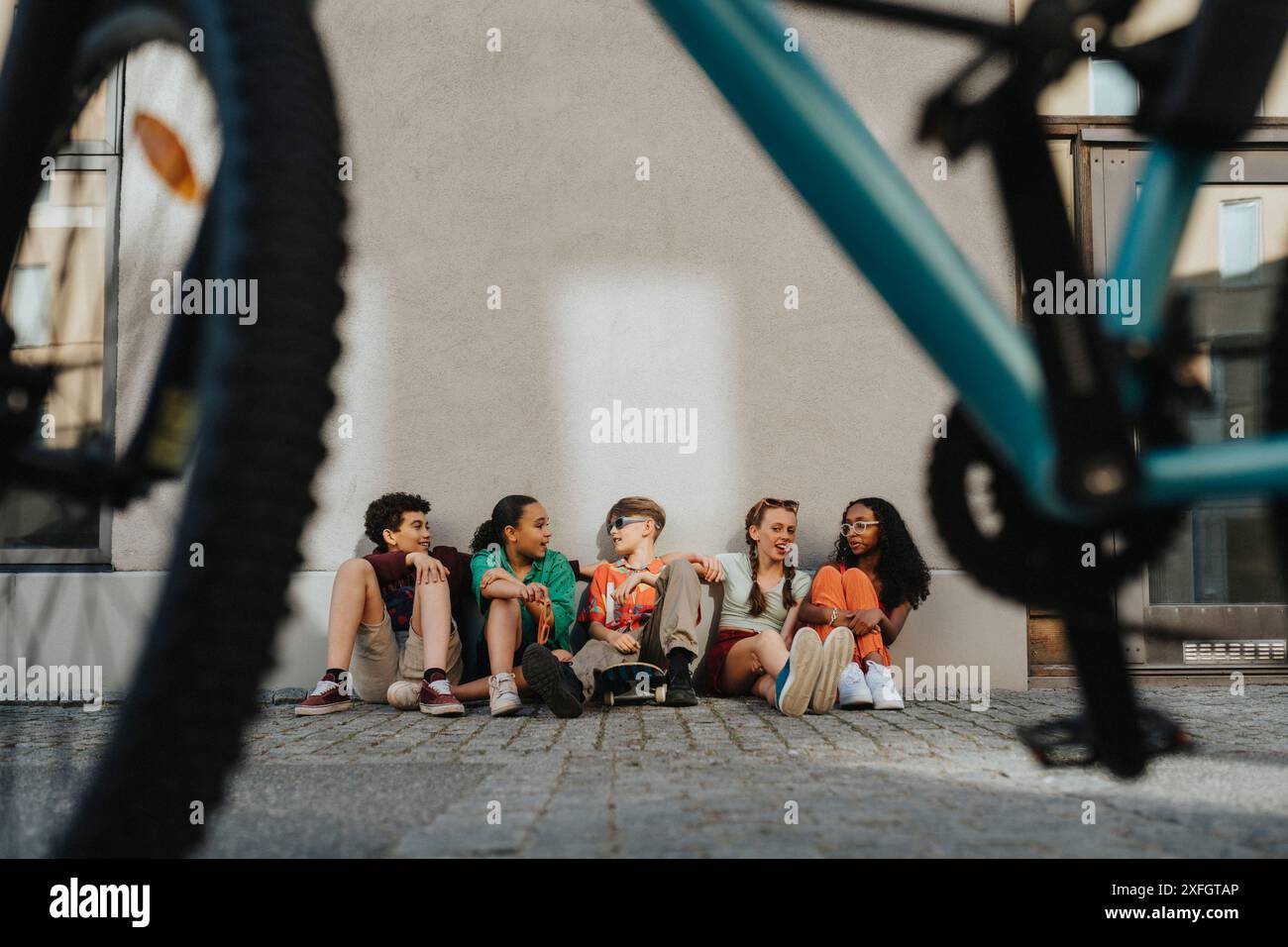 Eine Gruppe von Freunden sitzt auf dem Boden an der Wand Stockfoto
