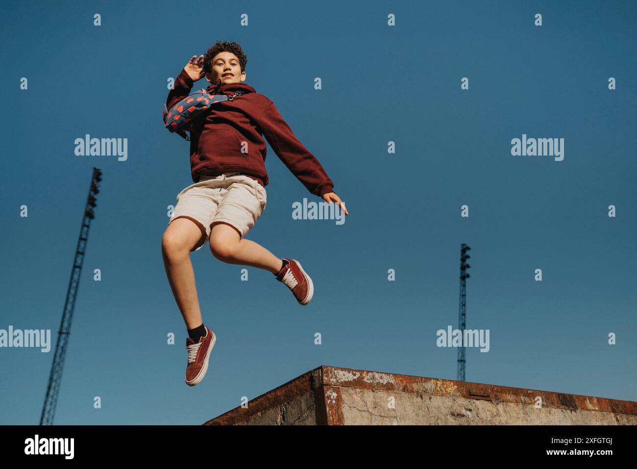Sorgloser Junge, der mitten in der Luft gegen den blauen Himmel springt Stockfoto
