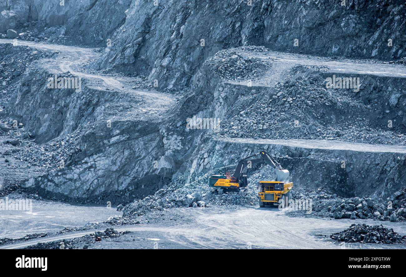 Bagger, der einen Müllwagen in einem mehrstufigen Diabasensteinbruch in Parekklisia, Zypern, beladen Stockfoto