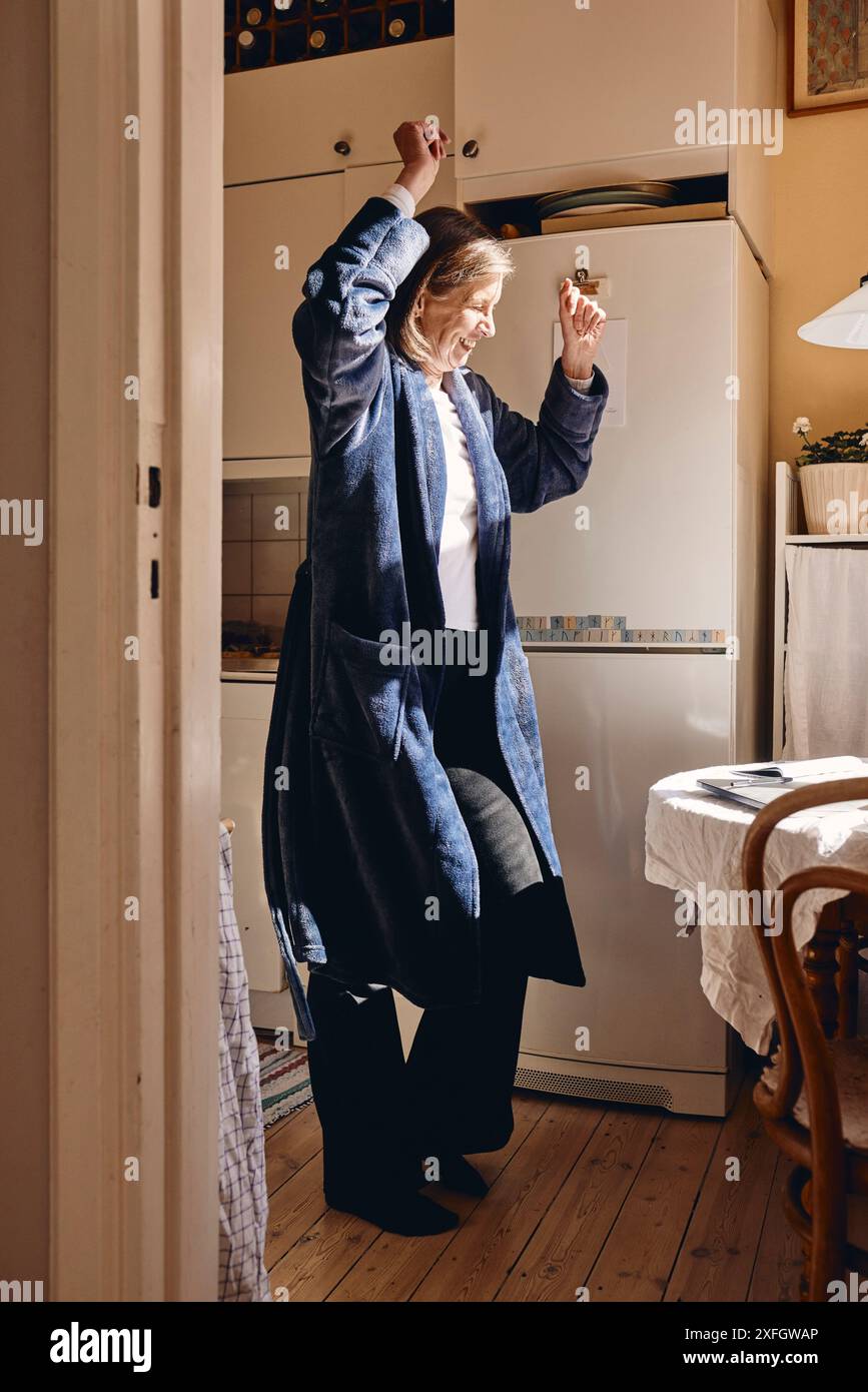 Glückliche Seniorin, die zu Hause in der Küche tanzt Stockfoto
