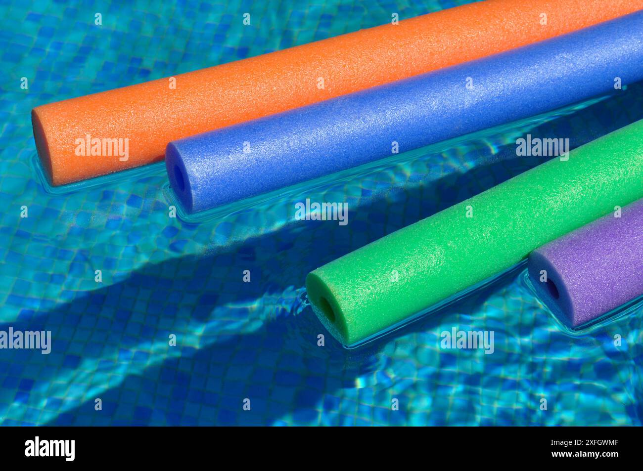 Farbenfrohe Polyethylen-Hohlschaum-Poolnudeln, die auf dem Wasser im Swimmingpool schwimmen Stockfoto