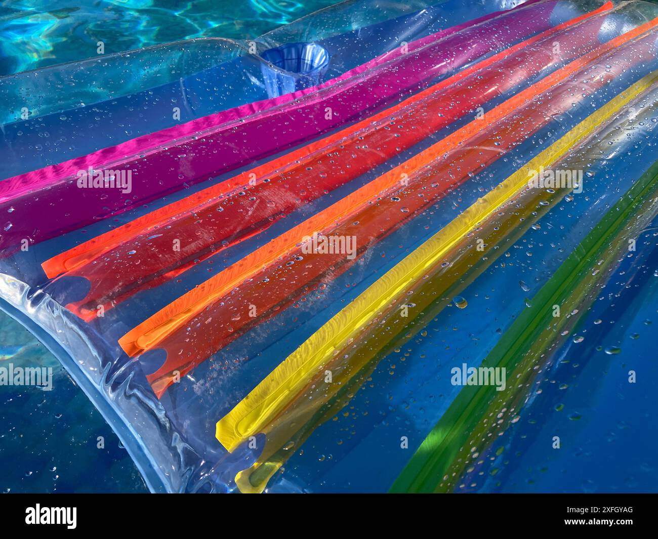 Sommer-Vibes, Regenbogenfarbene Feuchtlilo, die im Swimmingpool schwimmt, Nahaufnahme Stockfoto