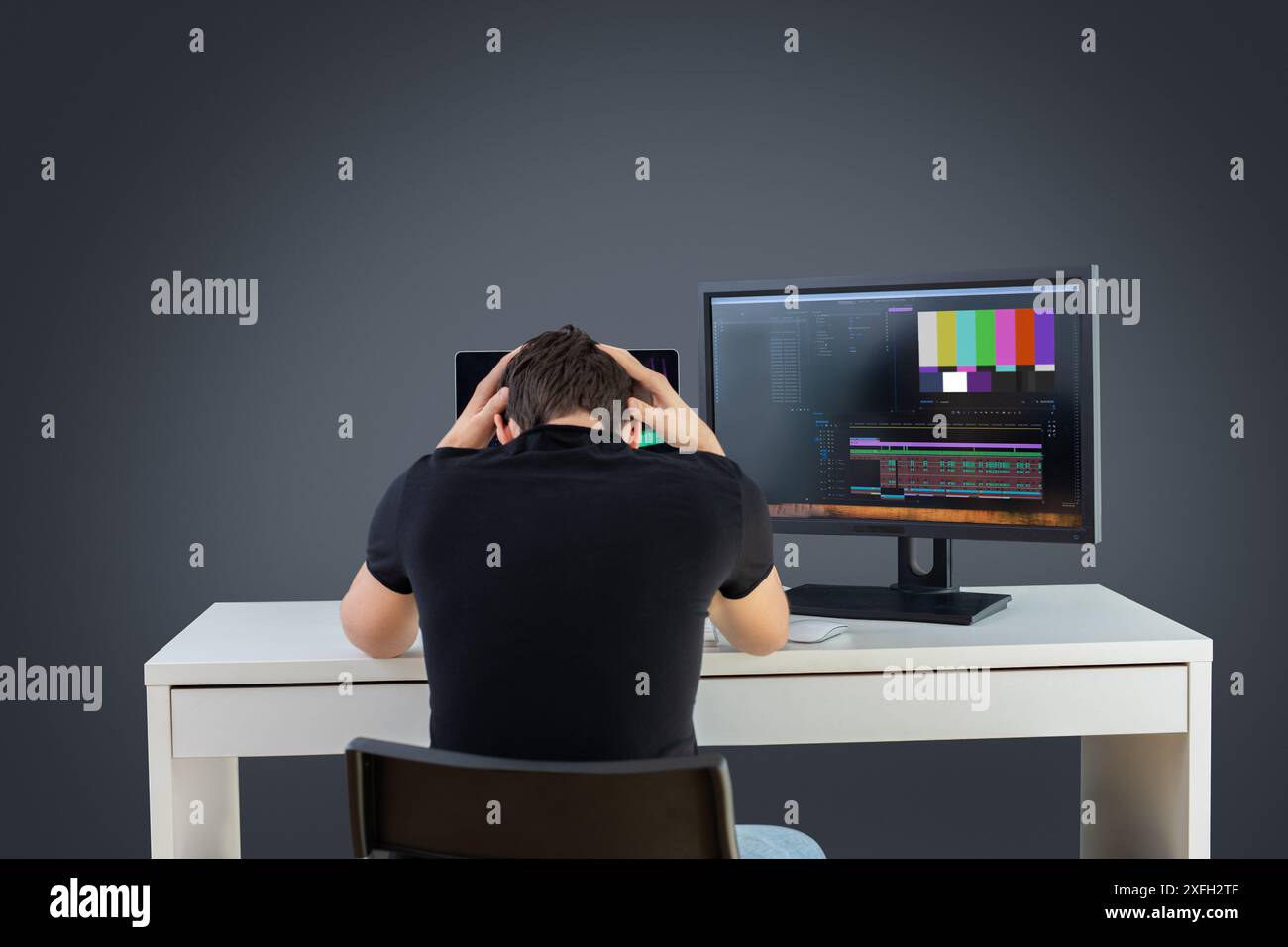 Videoredakteur sitzen verzweifelt vor dem Schreibtisch, während die Medien offline sind, während die Aufnahmen auf dem Computer verloren gingen, ohne die Hände über Kopf zu haben und frustriert zu sein Stockfoto