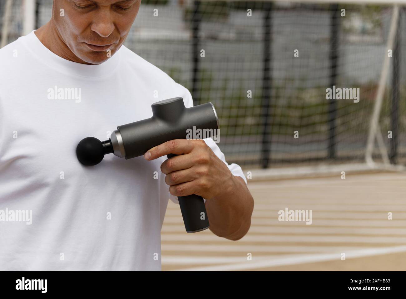 Sportmann, der die Brustmuskulatur massiert. Massagepistole für Athleten, tragbare kabellose professionelle Percussion Tiefengewebe Körper Muskelfaszie. Nahaufnahme. Kopieren Stockfoto