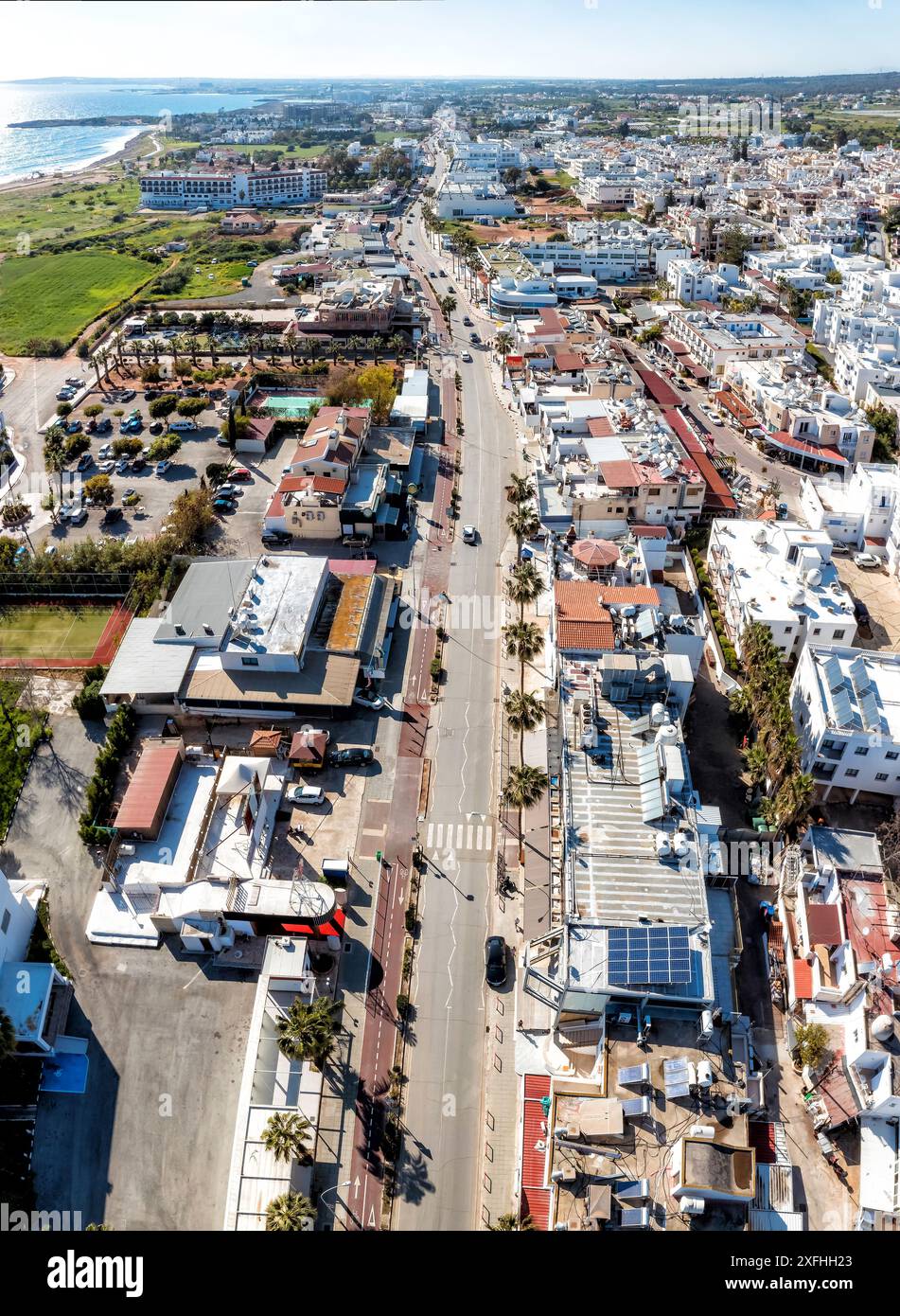 Blick aus der Vogelperspektive auf das Stadtzentrum von Ayia Napa mit einer leeren Straße, die an einem sonnigen Tag durch das Stadtzentrum zum Meer führt. Zypern Stockfoto