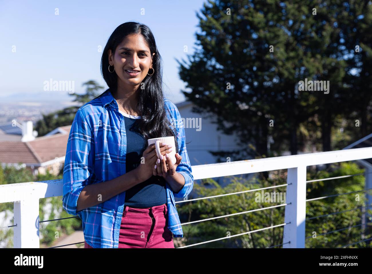 Kaffeetasse halten, Frau steht auf Balkon und genießt Morgensonne, Kopierraum Stockfoto