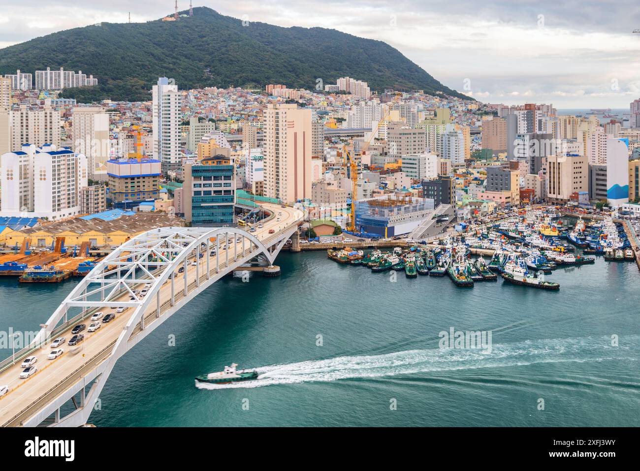 Malerischer Blick auf die Busandaegyo Bridge und den Hafen von Busan in Südkorea. Boot überquert den Hafen. Wunderschönes Stadtbild. Stockfoto