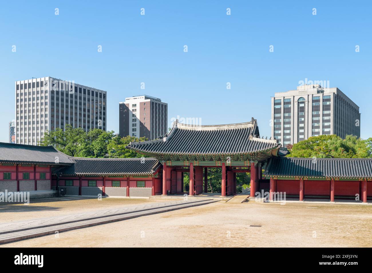 Malerischer Blick auf den Innenhof und das innere Jinseonmun-Tor des Changdeokgung-Palastes in Seoul, Südkorea. Moderne Gebäude sind auf blauem Himmel zu sehen. Stockfoto
