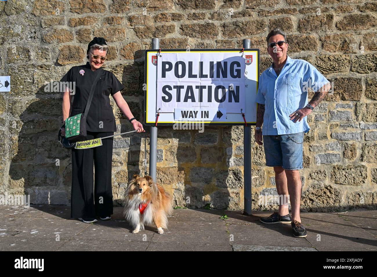 West Bay, Dorset, Großbritannien. Juli 2024. Bei der Wahl des Vereinigten Königreichs: Ein Shetland Sheepdog-Hund namens Tallahassee mit ihren Besitzern vor einer Wahlstation im Salt House in West Bay in Dorset. Bildnachweis: Graham Hunt/Alamy Live News Stockfoto