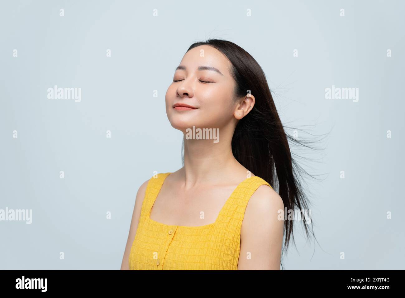 Lächelnde Frau im gelben Kleid vor neutralem Hintergrund Stockfoto