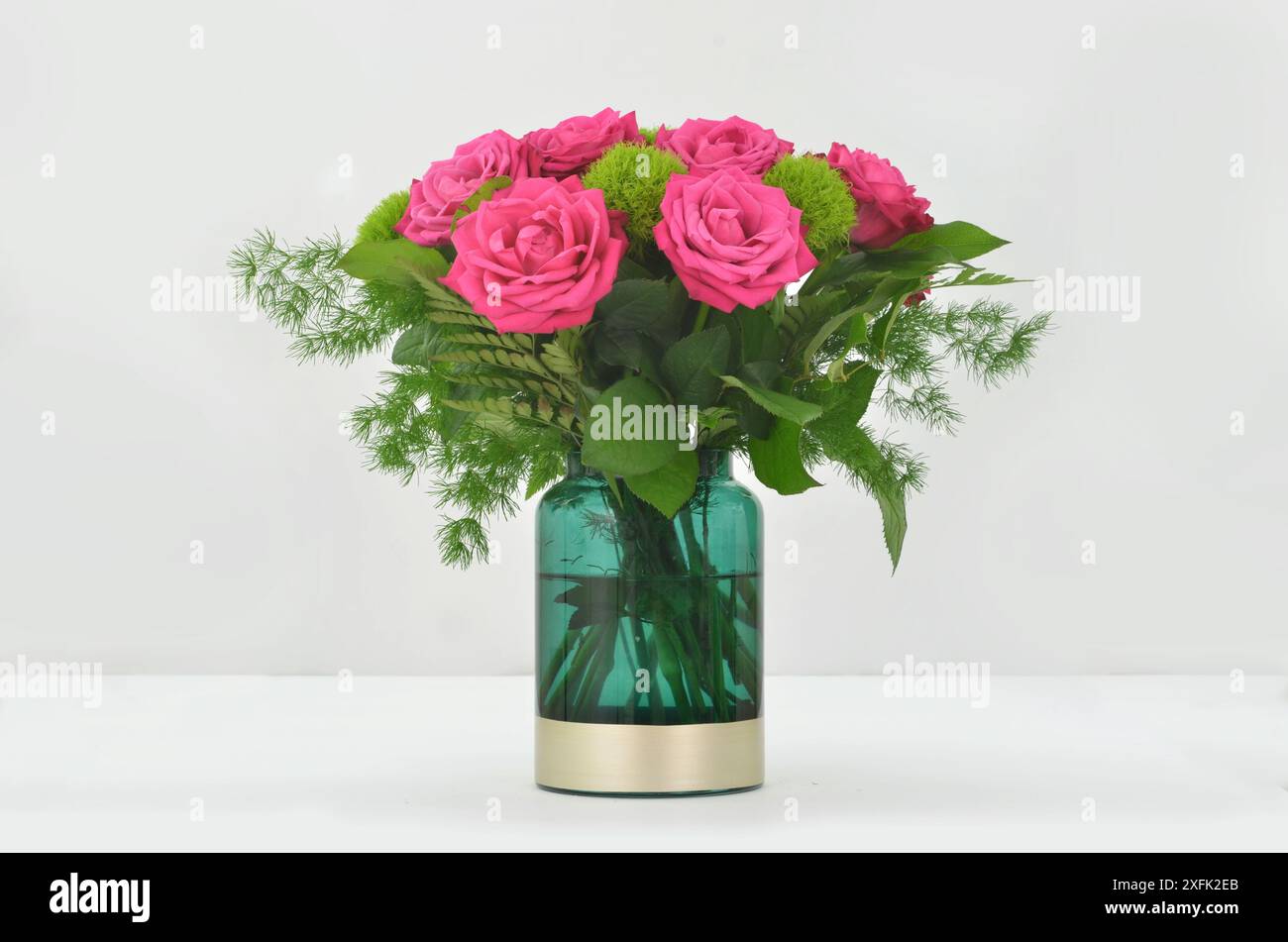 Eleganter Blumenstrauß aus rosa Rosen in grüner Vase auf hellem Hintergrund. Stockfoto