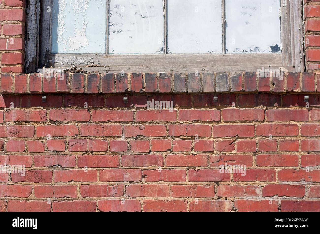Schmutzige und zerbröckelnde Ziegelsteine um einen Fenstervorsprung herum Stockfoto