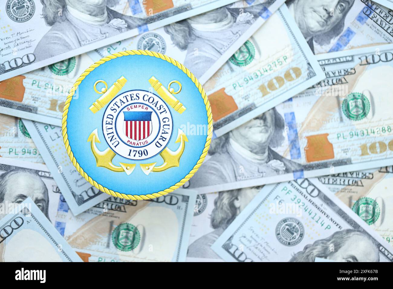 KIEW, UKRAINE - 26. JUNI 2024 Wappen der Küstenwache der Vereinigten Staaten auf große Mengen von US-Dollar-Banknoten aus nächster Nähe Stockfoto