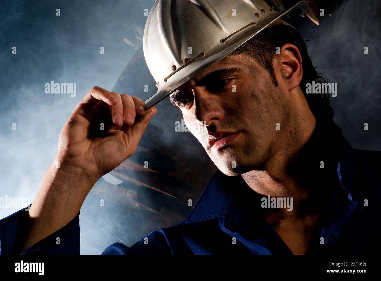 Junger Mann mit Aluminium Rumpf arbeiten in einer Mine in der Mitte eine starke Rauchentwicklung in einem hinterleuchteten Licht fotografiert Stockfoto