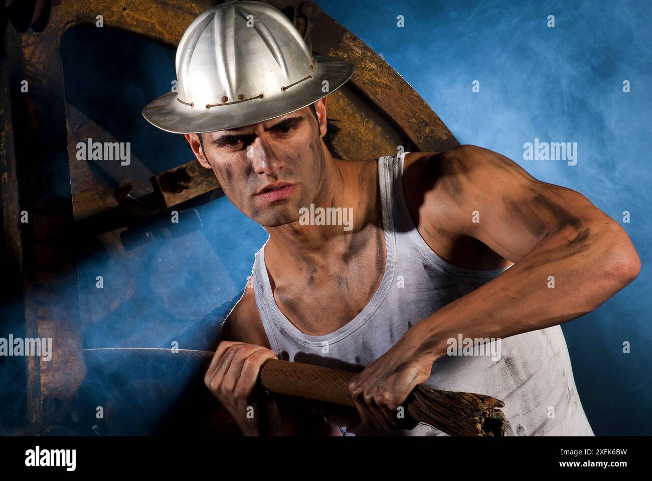 Arbeiter mit Aluminiumrumpf, der ein Stahlkabel in einer rauchigen Atmosphäre zieht Stockfoto