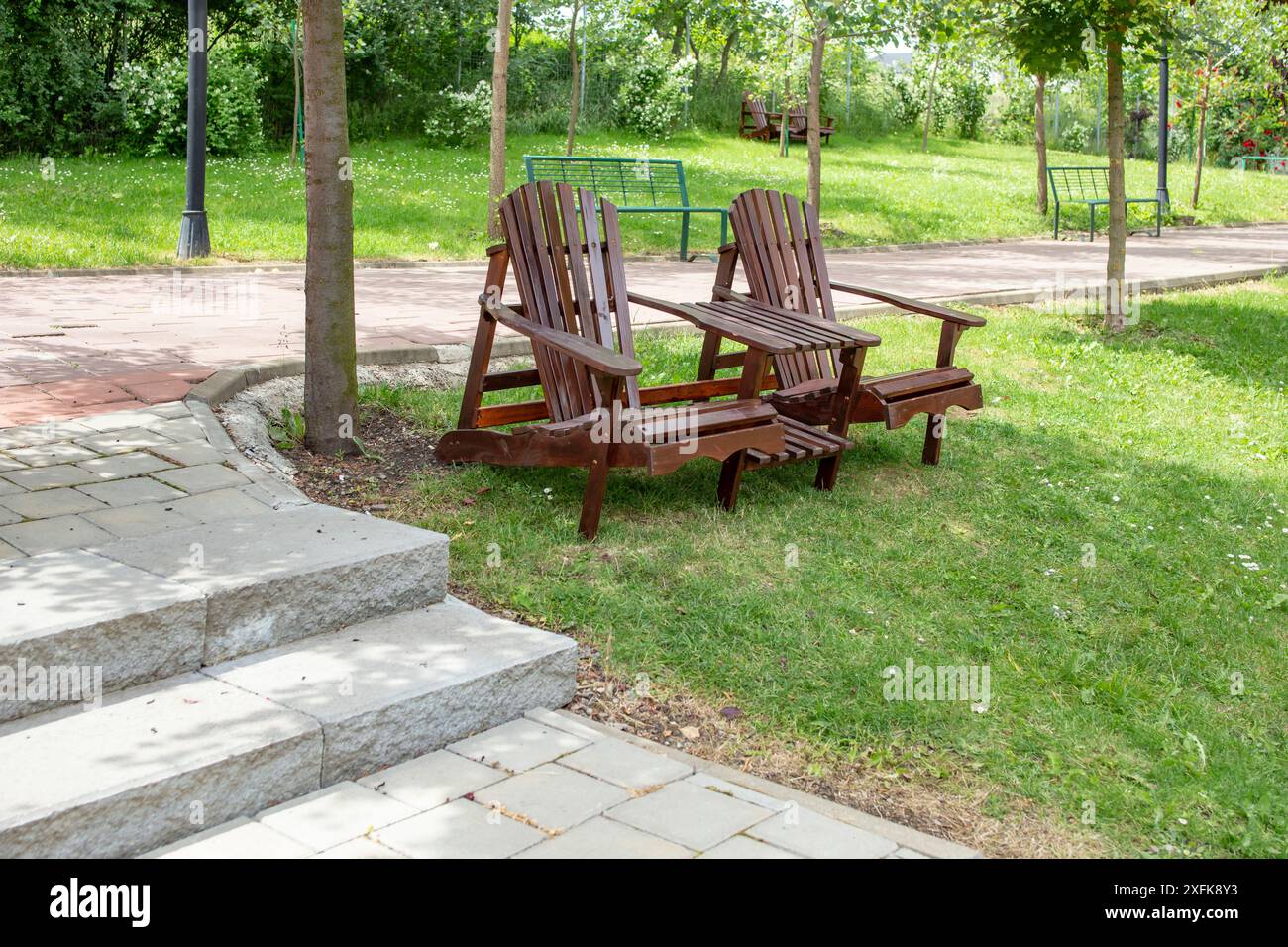 Adirondack Stühle mit Tisch in einem Park neben einer Gasse, Stockfoto