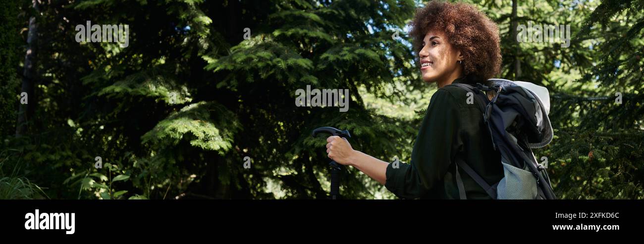Eine junge Frau wandert an einem Sommertag durch einen üppigen, grünen Wald. Stockfoto