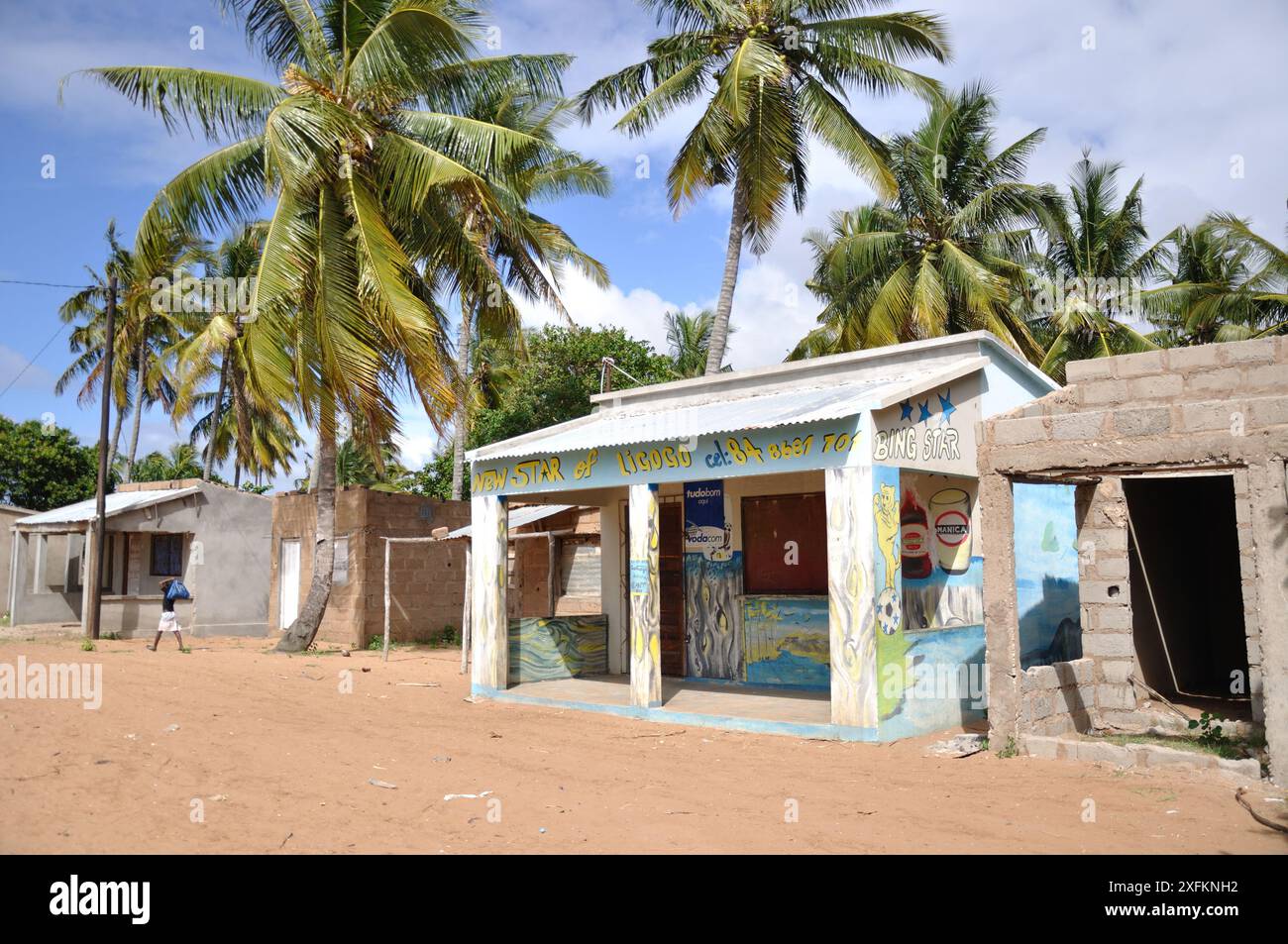 Kleiner Laden am Straßenrand, Ligogo, Inhambane, Mosambik - Gebäude im Bau; Palmen, Sandstraße. Der Shop ist noch geschlossen. Stockfoto