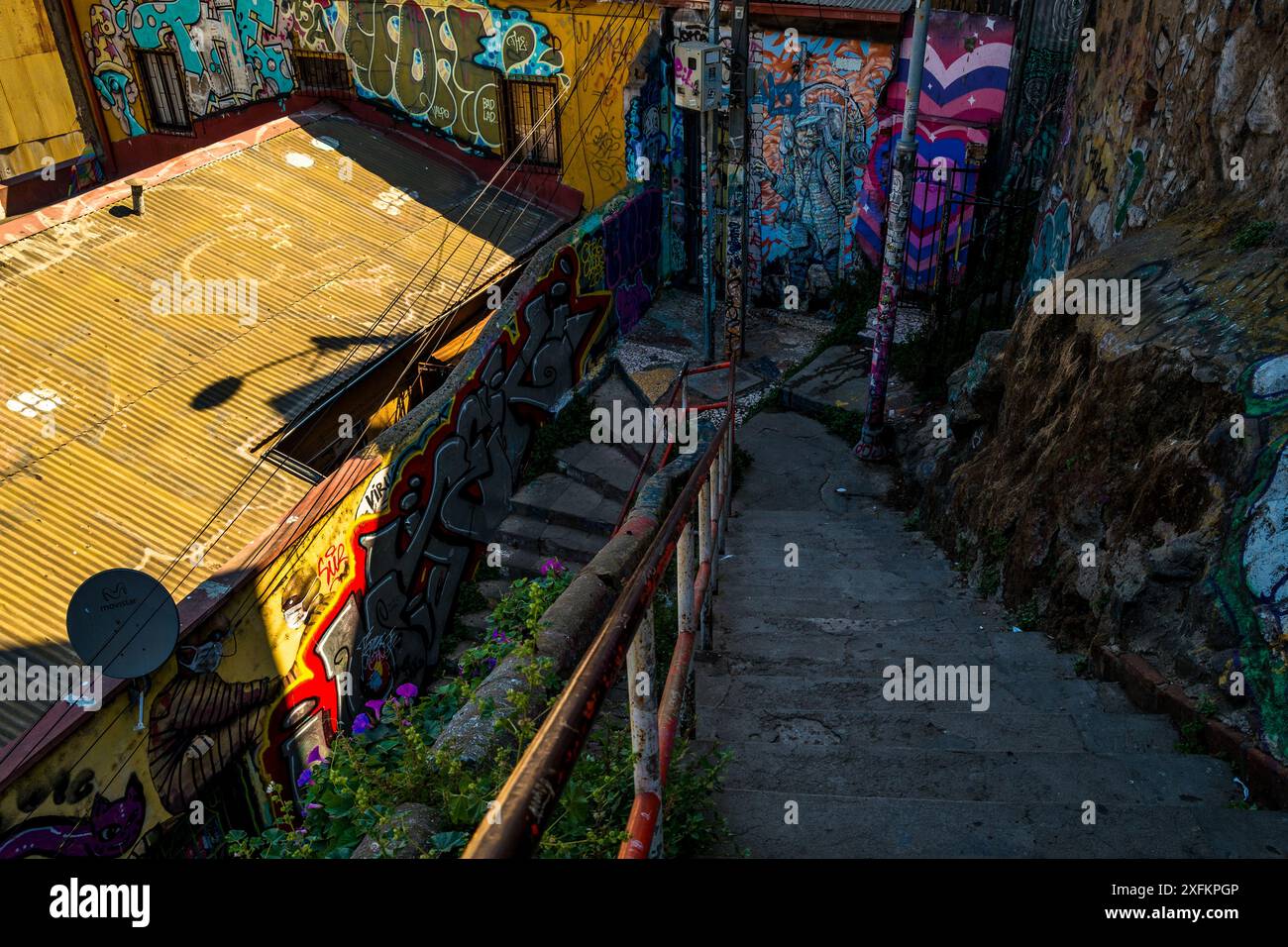 Auf dem Hügel Cerro Alegre in Valparaíso, Chile, befindet sich eine dunkle Treppe, umgeben von Graffiti-Kunstwerken. Stockfoto