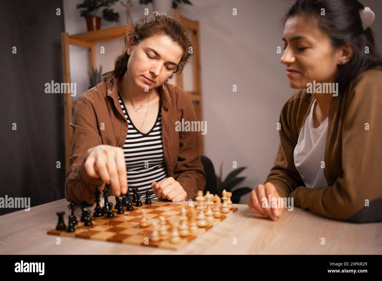 Weibliche Paare spielen zu Hause Schach, konzentriert und strategisch, verbringen gute Zeit miteinander Stockfoto