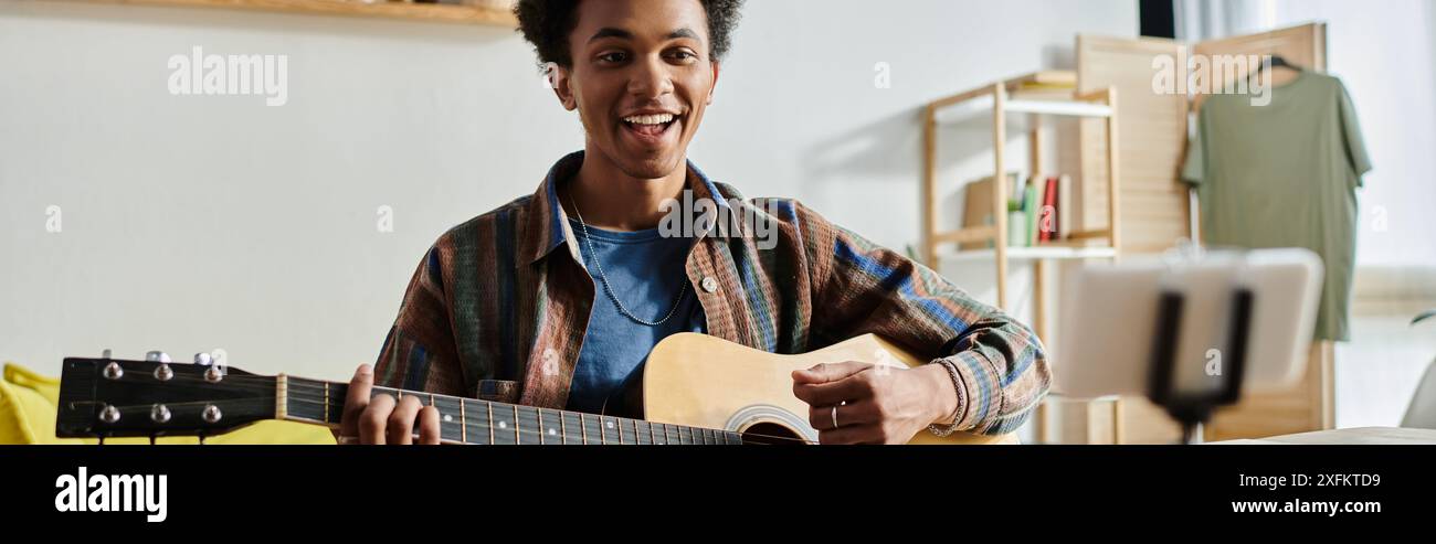 Junger Mann, der Akustikgitarre im Wohnzimmer spielt. Stockfoto